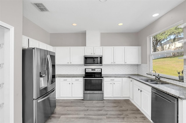 kitchen with stainless steel appliances, stone countertops, a sink, and visible vents