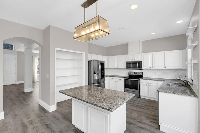 kitchen with stone counters, arched walkways, visible vents, appliances with stainless steel finishes, and a sink