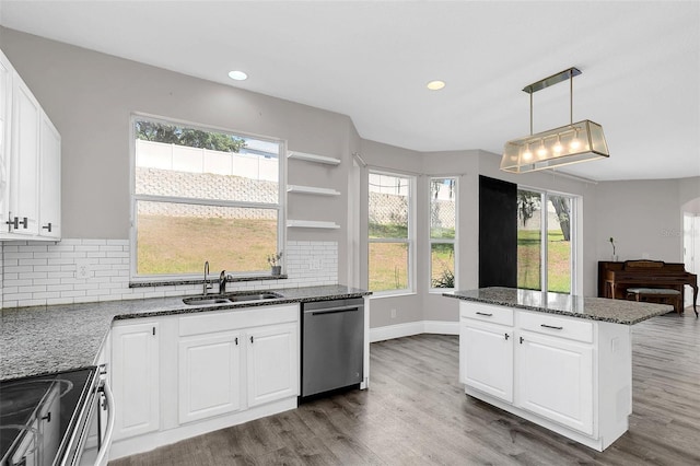 kitchen featuring appliances with stainless steel finishes, backsplash, a sink, and wood finished floors