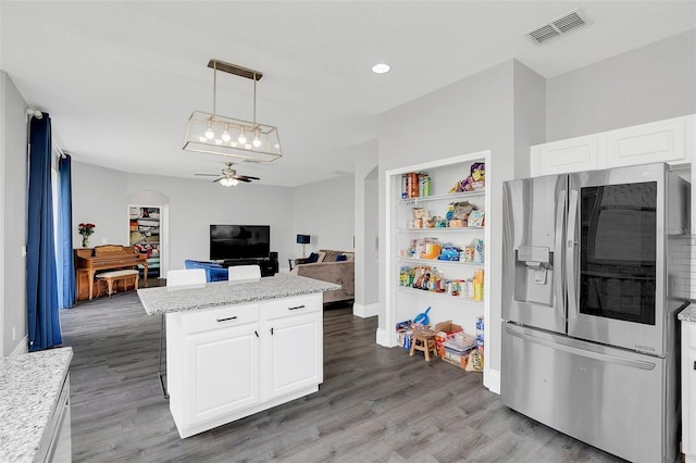 kitchen with light wood-style flooring, stainless steel fridge, visible vents, and a center island