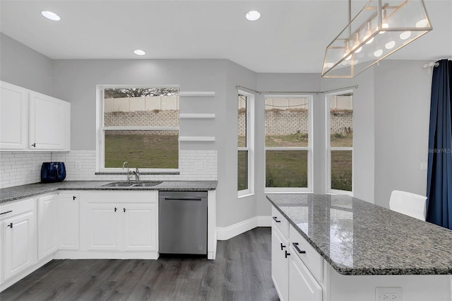 kitchen with dark wood-type flooring, a sink, stainless steel dishwasher, decorative backsplash, and dark stone counters