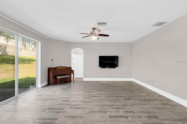 unfurnished living room with arched walkways, visible vents, and wood finished floors