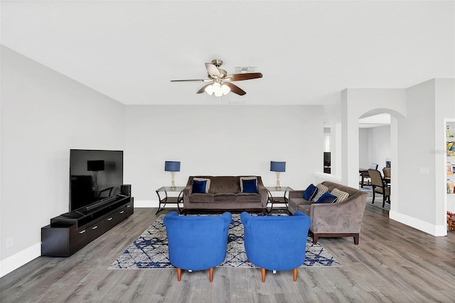 living area featuring baseboards, visible vents, arched walkways, and wood finished floors