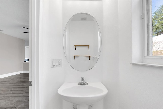 bathroom featuring visible vents, a sink, baseboards, and wood finished floors