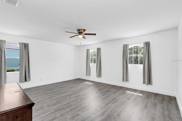 spare room featuring visible vents, ceiling fan, baseboards, and wood finished floors