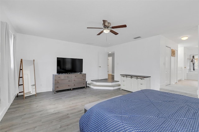 bedroom featuring a ceiling fan, visible vents, and wood finished floors