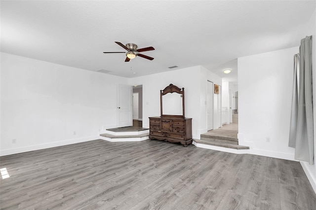 unfurnished living room with baseboards, visible vents, ceiling fan, and wood finished floors