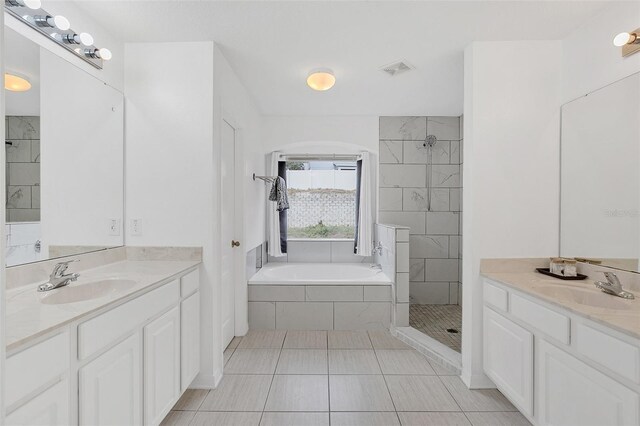 bathroom with tiled shower, a sink, visible vents, and a garden tub