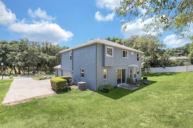 rear view of house featuring central AC unit, a garage, fence, decorative driveway, and a lawn