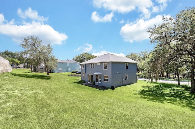 back of property with stucco siding and a yard