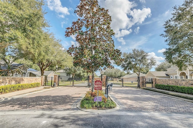 view of road featuring a gate, sidewalks, a gated entry, a residential view, and curbs