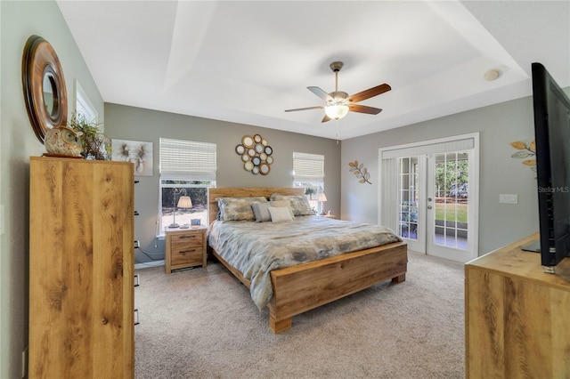 bedroom with a ceiling fan, french doors, a raised ceiling, light colored carpet, and access to exterior