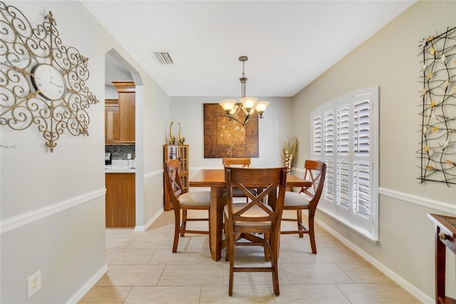 dining space with baseboards, visible vents, and a chandelier