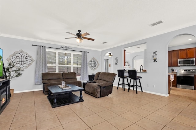 living area featuring light tile patterned floors, visible vents, and ornamental molding