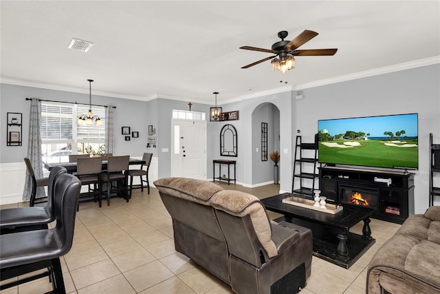 living room featuring arched walkways, ornamental molding, and a glass covered fireplace