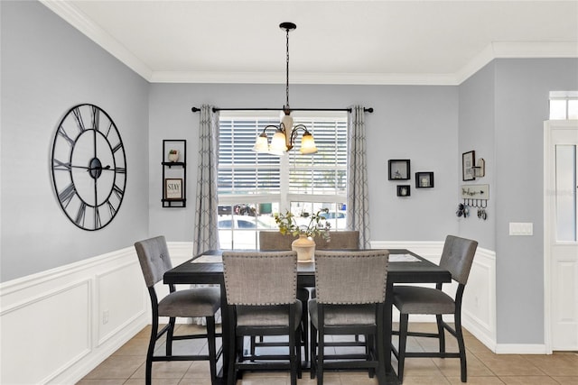 dining space featuring ornamental molding, a wealth of natural light, a chandelier, and a wainscoted wall