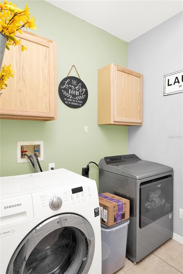 laundry room with cabinet space, light tile patterned floors, and washing machine and clothes dryer