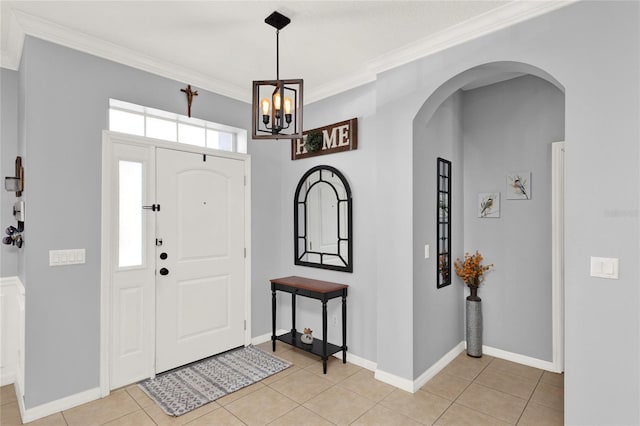 entrance foyer featuring ornamental molding, arched walkways, baseboards, and light tile patterned floors