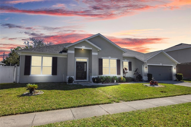 ranch-style home with a yard, stucco siding, concrete driveway, fence, and a garage