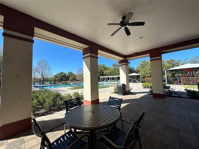 view of patio / terrace with a community pool, a ceiling fan, and outdoor dining space