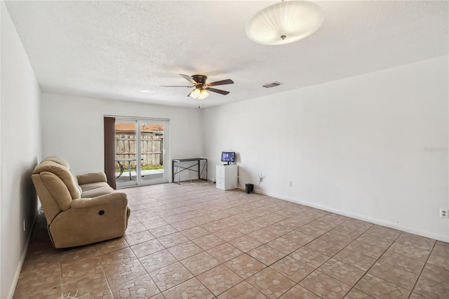 sitting room featuring a ceiling fan, visible vents, a textured ceiling, and baseboards