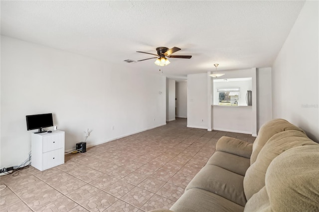 living room featuring light tile patterned floors, visible vents, baseboards, ceiling fan, and a textured ceiling