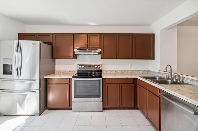 kitchen with appliances with stainless steel finishes, light countertops, a sink, and under cabinet range hood