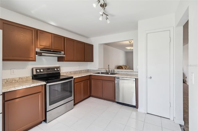 kitchen featuring brown cabinets, stainless steel appliances, light countertops, under cabinet range hood, and a sink