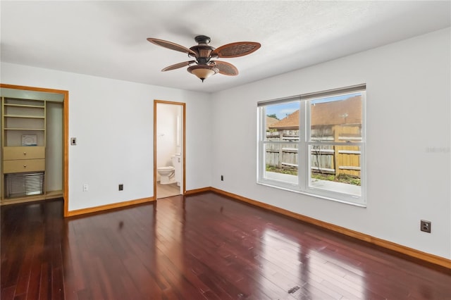 unfurnished bedroom featuring wood-type flooring, connected bathroom, baseboards, and ceiling fan