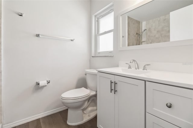 full bathroom featuring toilet, wood finished floors, vanity, baseboards, and walk in shower