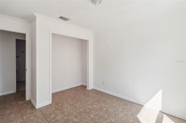 unfurnished bedroom featuring light tile patterned flooring, visible vents, baseboards, a closet, and crown molding