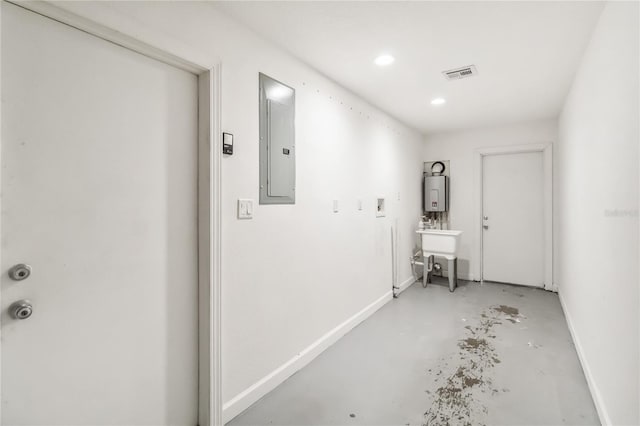 hallway with visible vents, water heater, electric panel, concrete floors, and baseboards