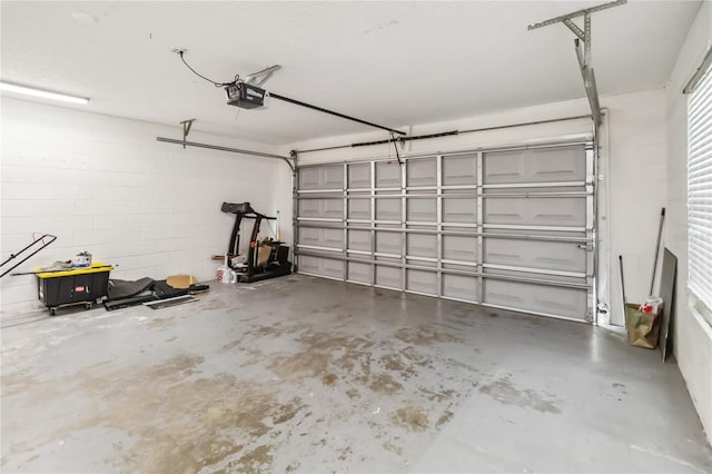 garage featuring concrete block wall and a garage door opener