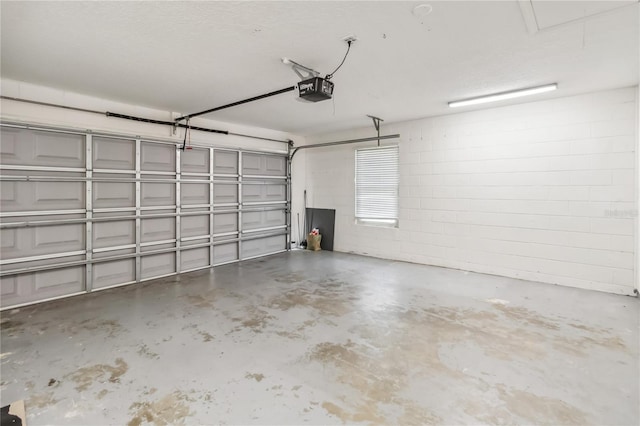 garage featuring concrete block wall and a garage door opener