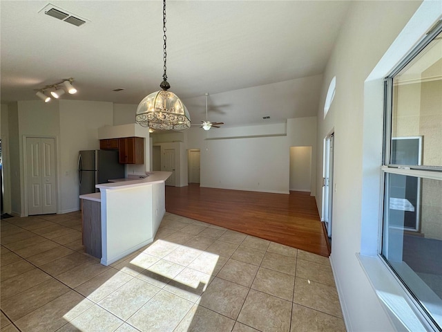 kitchen with light tile patterned floors, visible vents, light countertops, freestanding refrigerator, and decorative light fixtures