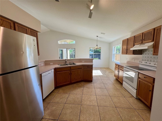 kitchen with white appliances, a peninsula, light countertops, under cabinet range hood, and a sink