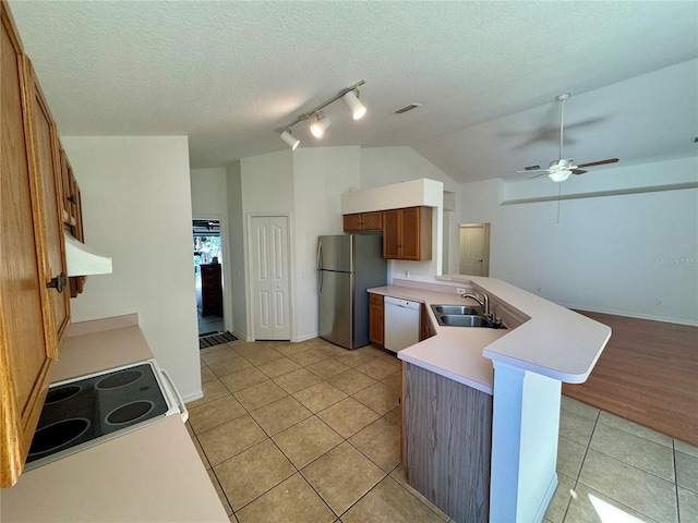 kitchen featuring a peninsula, a sink, light countertops, freestanding refrigerator, and dishwasher