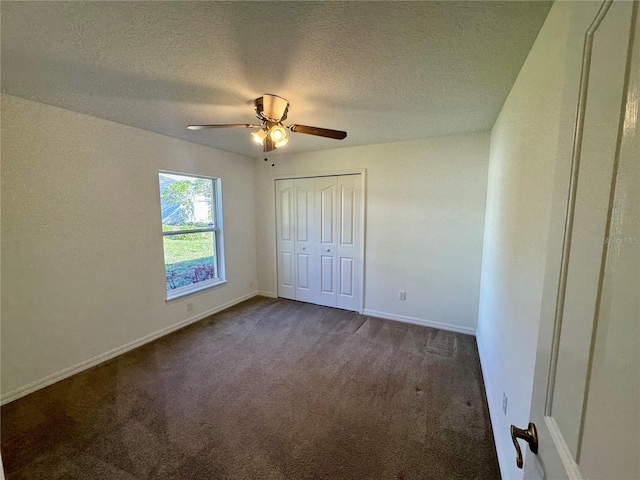 unfurnished bedroom featuring a textured ceiling, ceiling fan, carpet floors, baseboards, and a closet