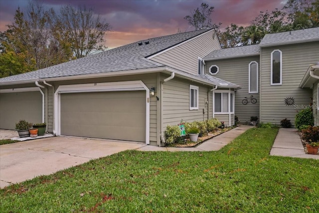 view of front of house featuring a yard, a shingled roof, an attached garage, and driveway