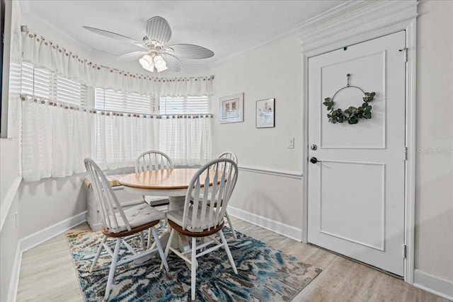 dining area featuring light wood finished floors, baseboards, ornamental molding, and ceiling fan