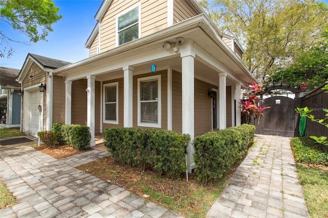 view of property exterior with a porch, a gate, and an attached garage