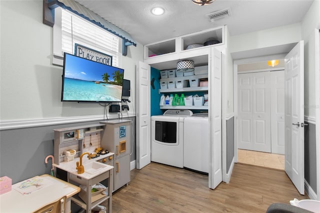 laundry area with laundry area, visible vents, light wood finished floors, and separate washer and dryer