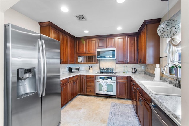 kitchen with stainless steel appliances, light countertops, visible vents, decorative backsplash, and a sink