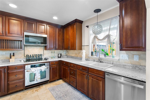 kitchen with hanging light fixtures, appliances with stainless steel finishes, backsplash, and a sink