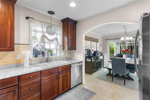 kitchen featuring stainless steel appliances, a sink, hanging light fixtures, and decorative backsplash