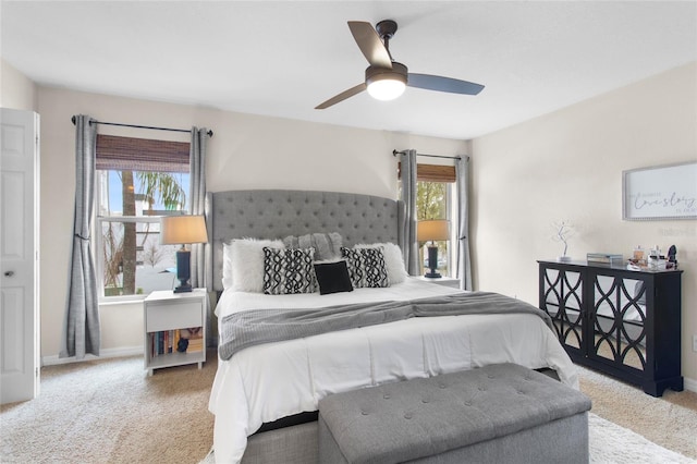 carpeted bedroom with ceiling fan, multiple windows, and baseboards