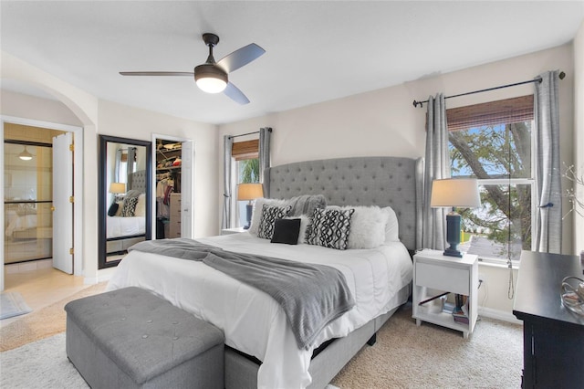 carpeted bedroom featuring a ceiling fan, a closet, a spacious closet, and baseboards