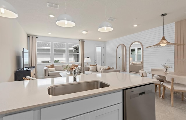 kitchen with decorative light fixtures, visible vents, stainless steel dishwasher, open floor plan, and a sink