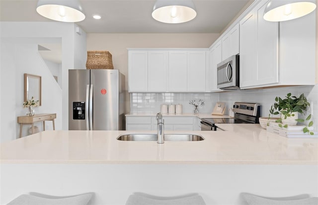 kitchen featuring a sink, white cabinetry, light countertops, appliances with stainless steel finishes, and tasteful backsplash