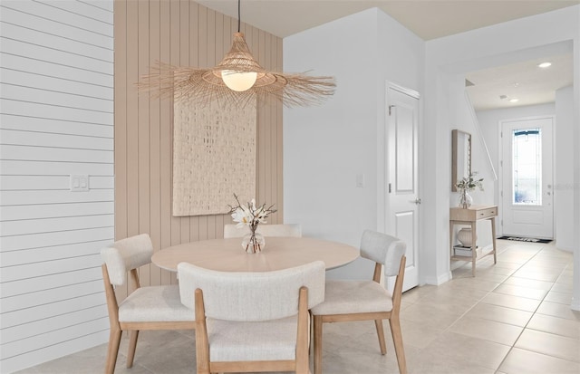 dining space featuring light tile patterned floors and wood walls